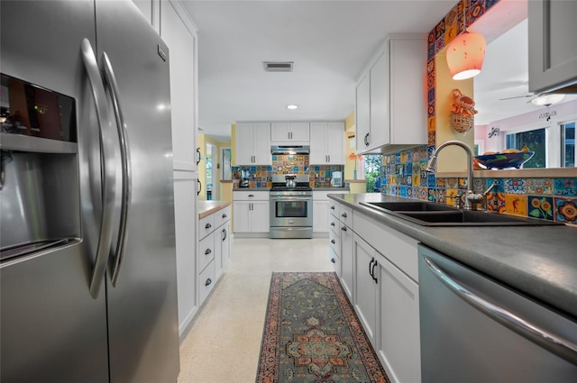 kitchen with stainless steel appliances, tasteful backsplash, visible vents, a sink, and under cabinet range hood