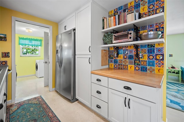 kitchen featuring washing machine and dryer, butcher block countertops, white cabinetry, open shelves, and stainless steel fridge