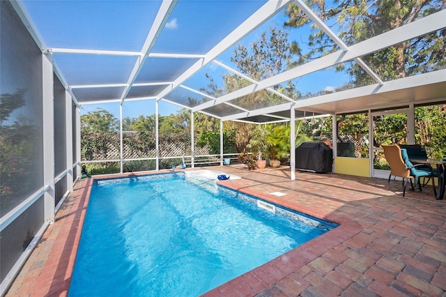 pool featuring glass enclosure, a patio, and area for grilling