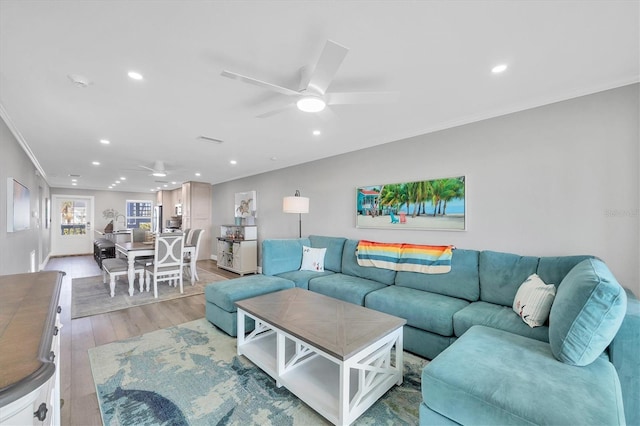 living area with light wood-style floors, ornamental molding, a ceiling fan, and recessed lighting