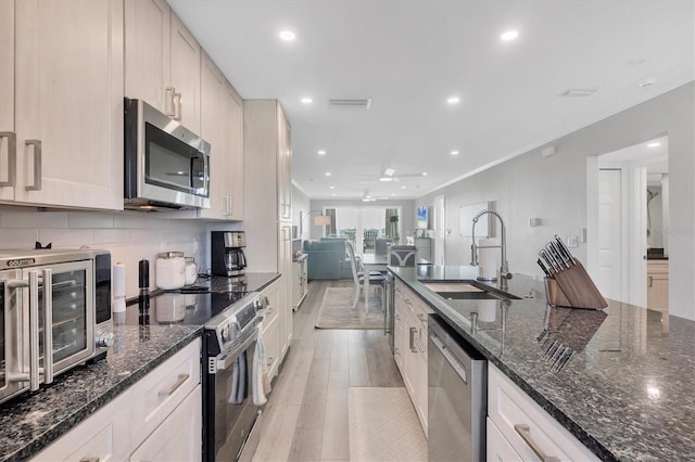 kitchen featuring stainless steel appliances, a sink, visible vents, ornamental molding, and backsplash