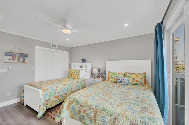 bedroom with wood finished floors, visible vents, baseboards, a closet, and crown molding