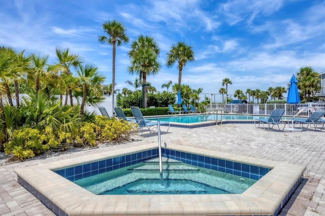 pool with fence, a community hot tub, and a patio