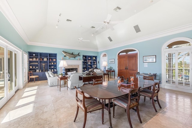 dining area with arched walkways, a fireplace, visible vents, built in features, and ornamental molding