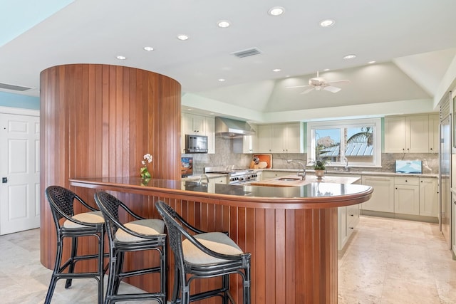 kitchen featuring visible vents, range, lofted ceiling, wall chimney range hood, and a sink