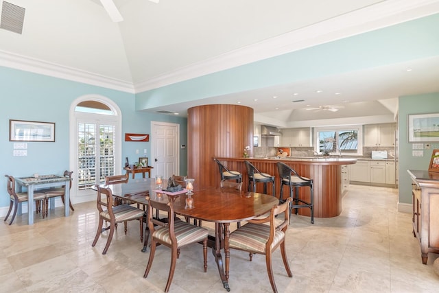 dining space featuring high vaulted ceiling, baseboards, visible vents, and crown molding