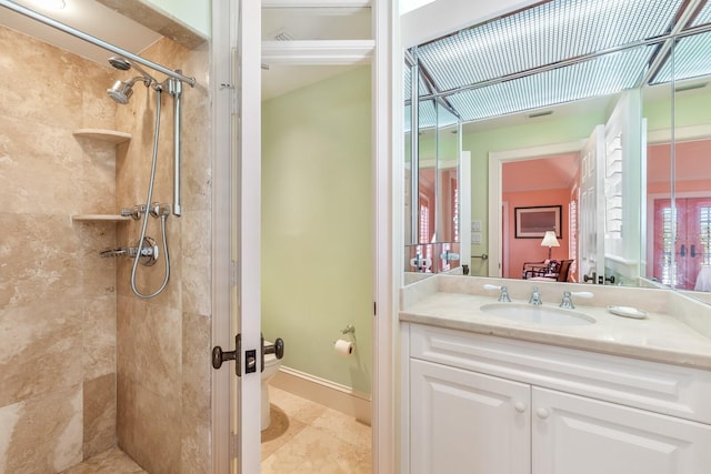 bathroom featuring tiled shower, vanity, and baseboards