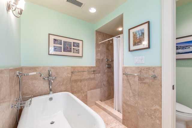 full bath with tile walls, visible vents, toilet, wainscoting, and tiled shower