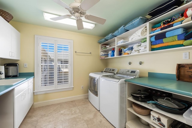 clothes washing area featuring cabinet space, baseboards, ceiling fan, washing machine and dryer, and a sink