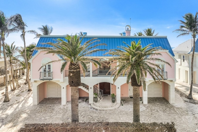 view of front of house with an attached garage, a balcony, and stucco siding