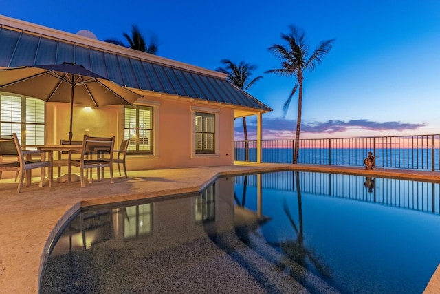 view of swimming pool with a water view, a patio area, outdoor dining area, and a fenced in pool