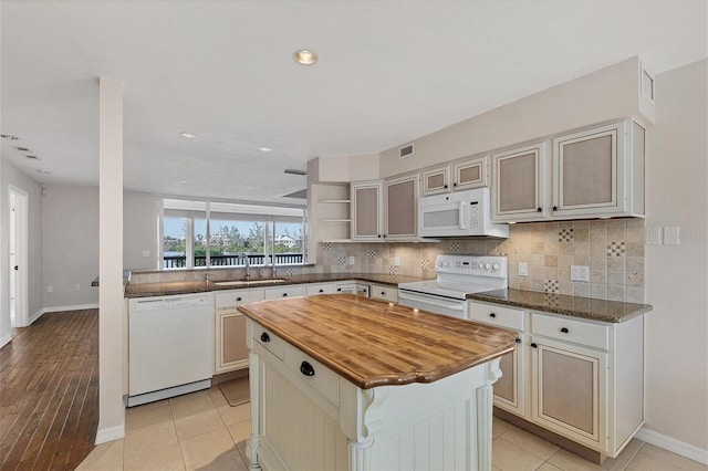 kitchen featuring a sink, white appliances, backsplash, and butcher block counters