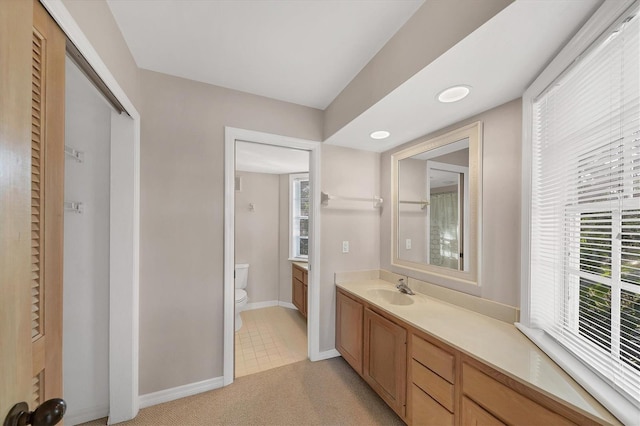 bathroom with toilet, vanity, and baseboards