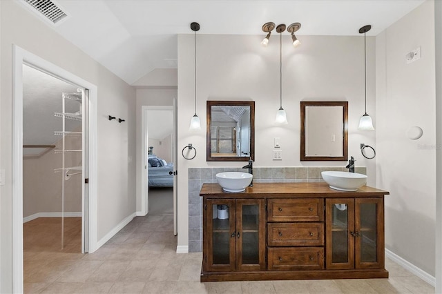 ensuite bathroom featuring lofted ceiling, double vanity, ensuite bath, and a sink