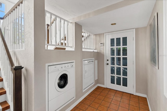 clothes washing area featuring tile patterned flooring, laundry area, washer and clothes dryer, and baseboards