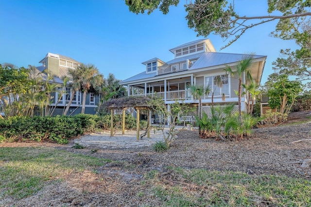 back of property with covered porch, metal roof, and a balcony