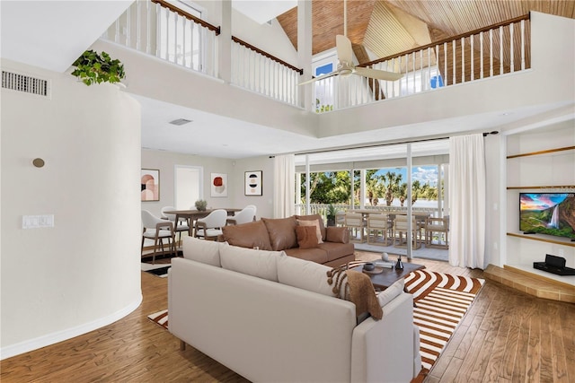 living room with visible vents, baseboards, ceiling fan, hardwood / wood-style floors, and high vaulted ceiling