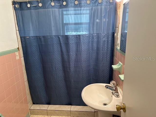 1417 Terry Ave, Punta Gorda, FL 33980 - full bathroom featuring a shower with shower curtain, a sink, tile walls, wainscoting, and tile patterned floors