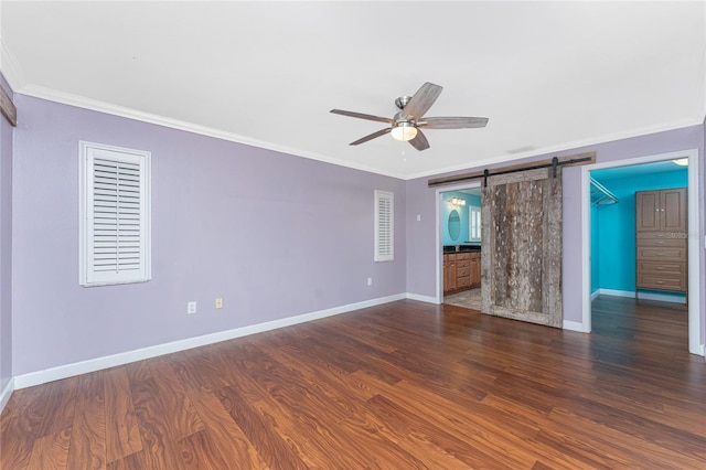 unfurnished room with a barn door, a ceiling fan, wood finished floors, and crown molding