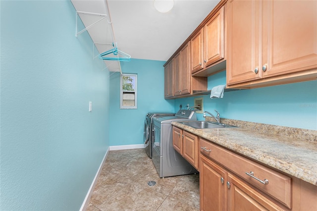 washroom featuring washer and dryer, baseboards, cabinet space, and a sink