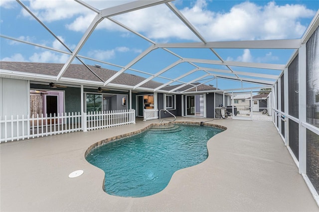 outdoor pool featuring glass enclosure, a patio area, fence, and ceiling fan