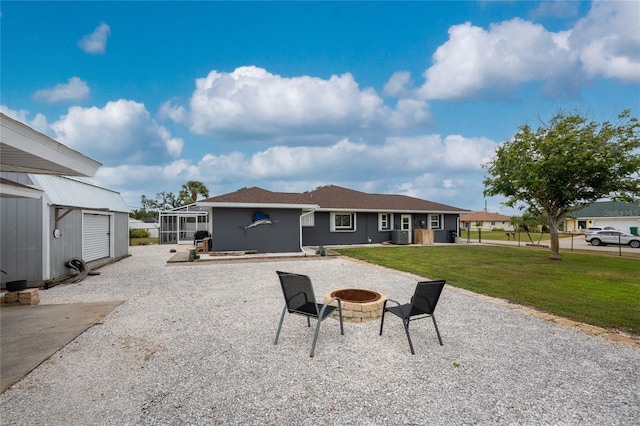 rear view of property with a lanai, an outdoor fire pit, a lawn, stucco siding, and an outbuilding