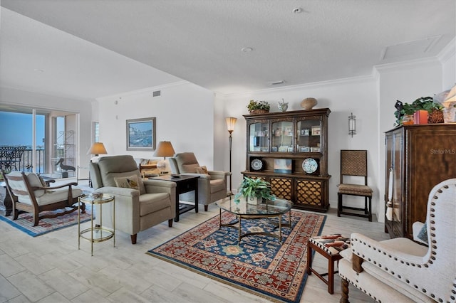 living area featuring ornamental molding, light wood-type flooring, visible vents, and a textured ceiling