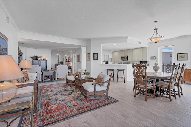 dining room with ornamental molding, light wood-type flooring, visible vents, and a textured ceiling