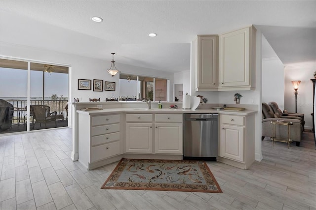 kitchen featuring light wood-style flooring, a peninsula, a sink, light countertops, and stainless steel dishwasher