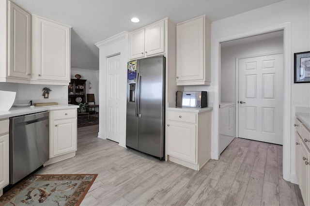 kitchen featuring stainless steel appliances, light countertops, white cabinetry, and independent washer and dryer