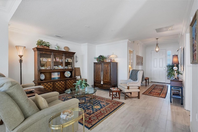 living room with visible vents, crown molding, and light wood-style flooring