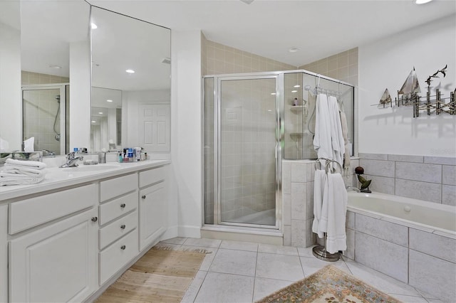 full bathroom featuring a stall shower, tile patterned flooring, tiled bath, and vanity