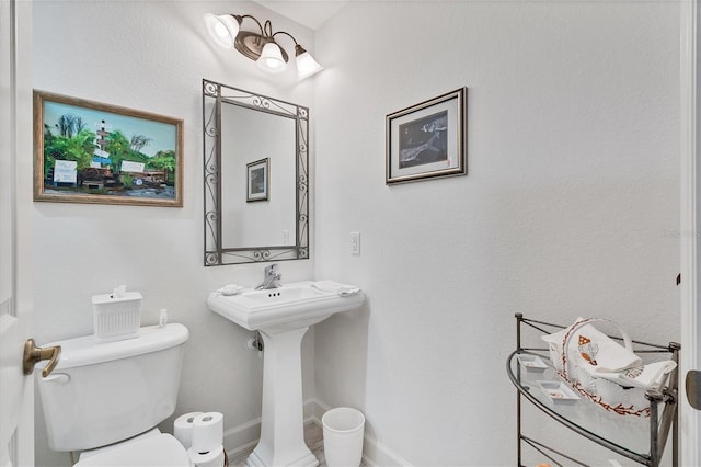 bathroom featuring baseboards, a sink, and toilet