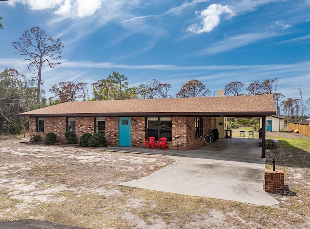 ranch-style home with driveway, a shingled roof, a carport, and brick siding