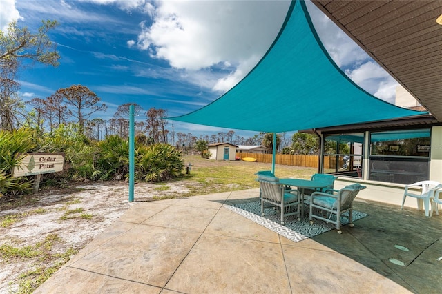 view of patio featuring an outbuilding, fence, outdoor dining space, and a storage unit