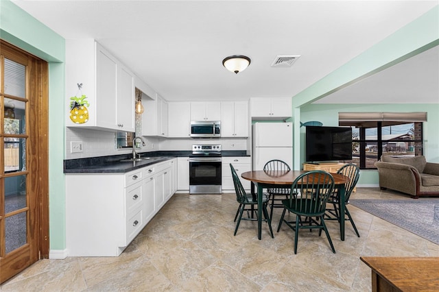 kitchen with stainless steel appliances, a sink, visible vents, white cabinets, and dark countertops