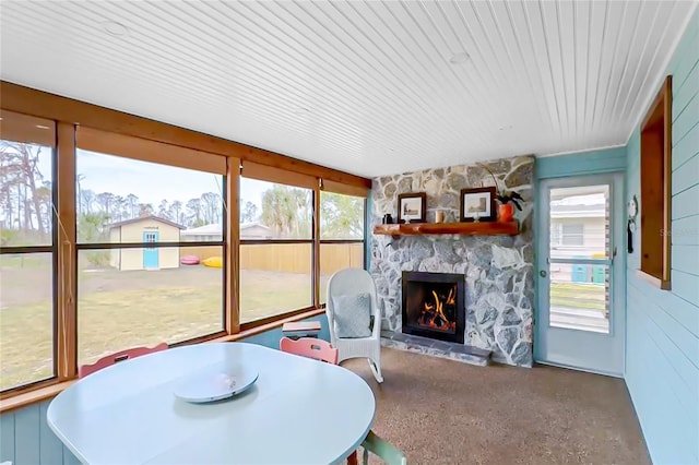 sunroom featuring a stone fireplace and a healthy amount of sunlight