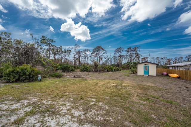 view of yard featuring a storage shed, fence, and an outdoor structure