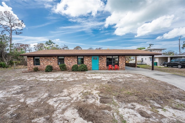 single story home featuring a carport, brick siding, and driveway