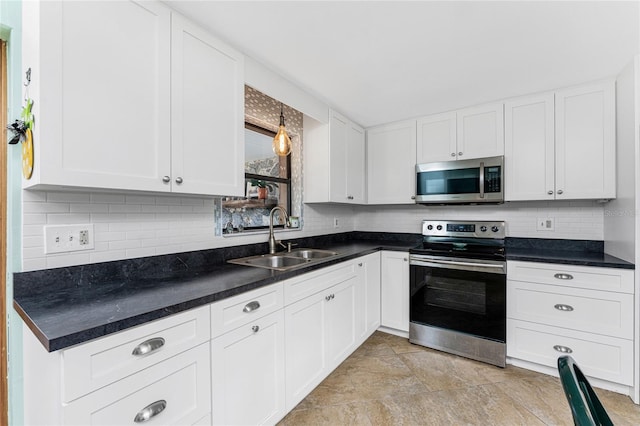 kitchen featuring tasteful backsplash, dark countertops, appliances with stainless steel finishes, white cabinets, and a sink