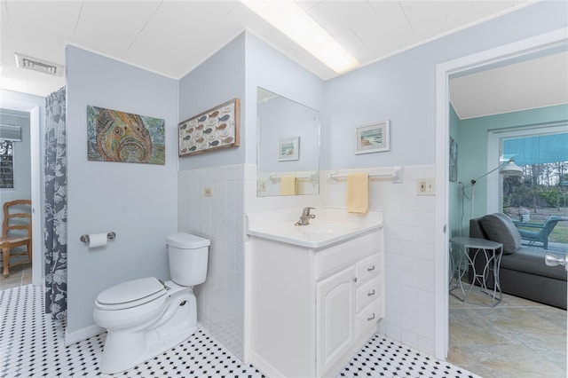 bathroom featuring visible vents, tile walls, toilet, and vanity