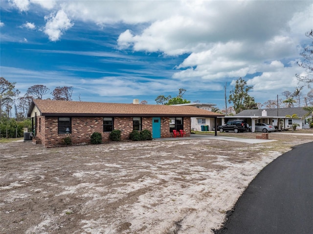 ranch-style home with a carport, cooling unit, and brick siding