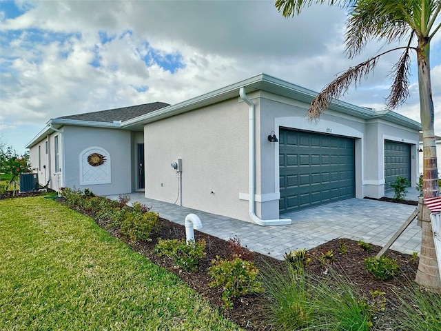 view of property exterior featuring central AC, a yard, an attached garage, and stucco siding