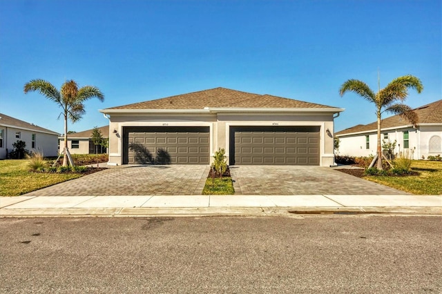 view of front facade with a garage, decorative driveway, and stucco siding