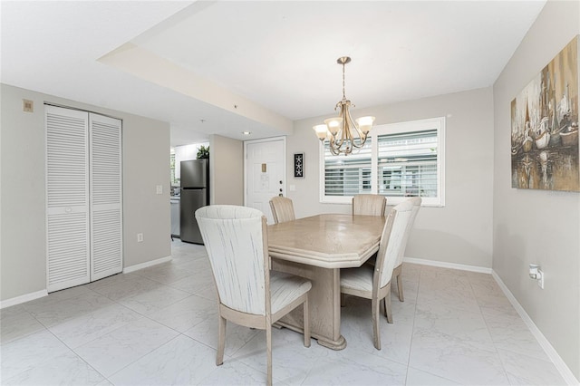 dining space featuring marble finish floor, an inviting chandelier, and baseboards