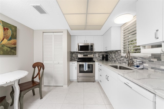 kitchen featuring stainless steel appliances, a sink, visible vents, light stone countertops, and tasteful backsplash