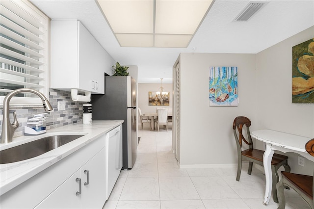 kitchen featuring tasteful backsplash, visible vents, dishwasher, white cabinetry, and a sink