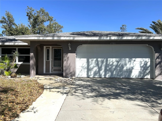 single story home with stucco siding, concrete driveway, and a garage