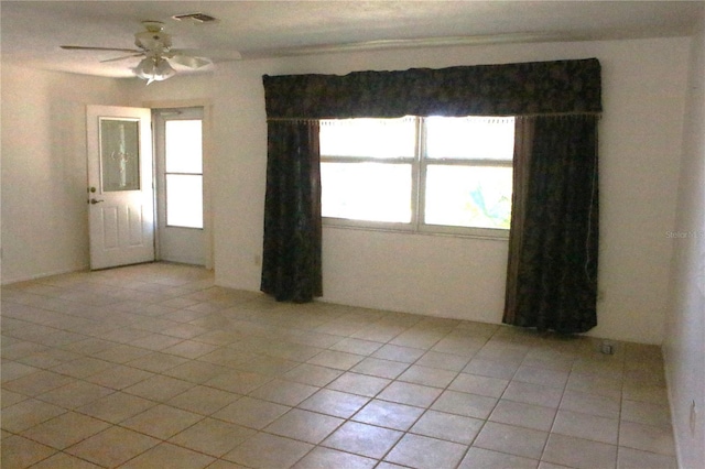 empty room with visible vents, light tile patterned flooring, and a ceiling fan