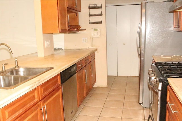 kitchen featuring light tile patterned floors, brown cabinetry, a sink, light countertops, and appliances with stainless steel finishes